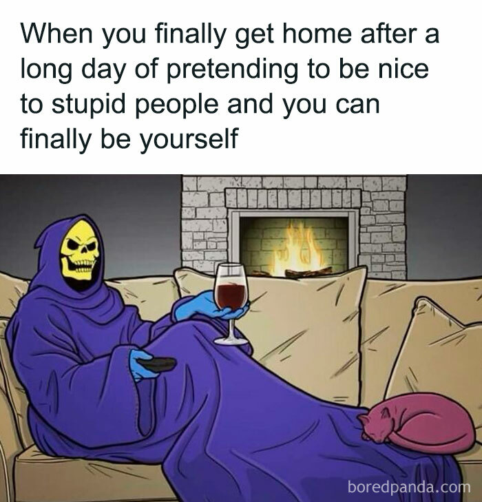 Skeleton in a robe relaxing with wine and a cat by the fireplace, capturing introvert struggles after social exhaustion.