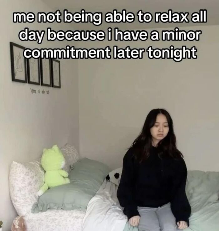 Introvert feeling socially exhausted, sitting on a bed with a stuffed toy, captioning a struggle with minor commitments.