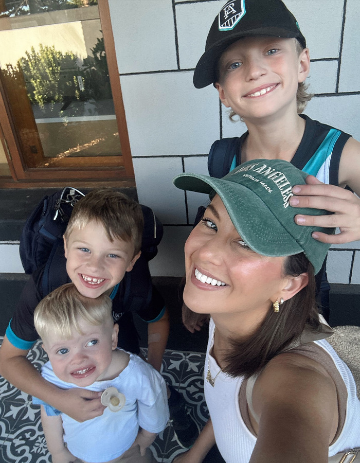 Woman with three children smiling outside, wearing casual hats; related to a restaurant incident with a toddler.