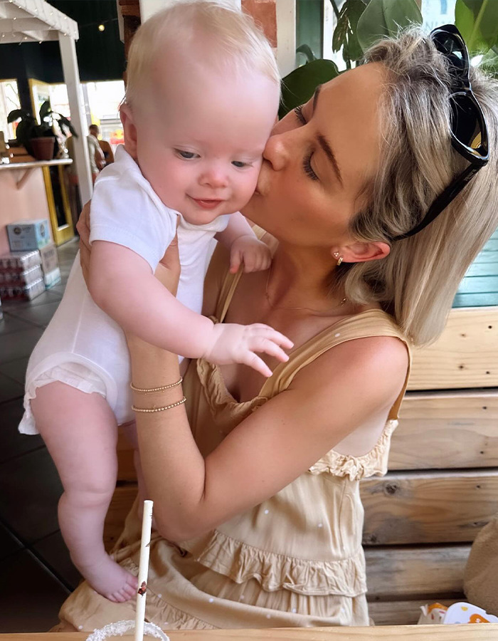 Mother embraces toddler in a restaurant setting, reflecting on a recent parenting incident.