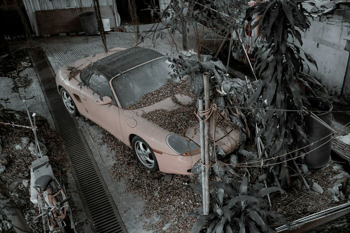 Abandoned car covered in leaves in a neglected urban area, evoking memories shared by first responders.
