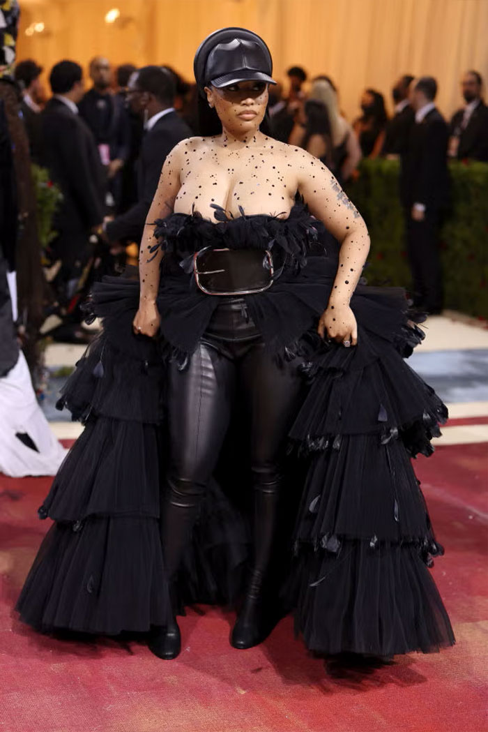 Celebrity wearing a bold black outfit with leather pants and layered tulle at the Met Gala showcasing bizarre fashion.
