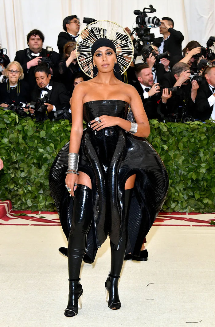 Celebrity in a bold black shiny outfit and avant-garde headpiece at the Met Gala showcasing bizarre Met Gala outfits style.