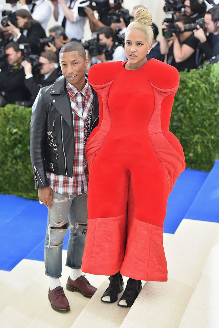 Two celebrities posing on the Met Gala red carpet, one wearing a bold red avant-garde outfit, highlighting failed fashion attempts.