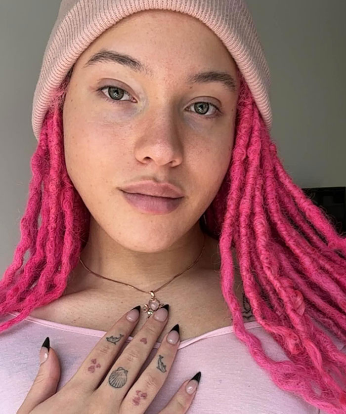 Young person with pink dreadlocks and a beanie, showing tattoos and nails, representing Robert De Niro's transgender daughter. Young person with pink dreadlocks and a beanie, showing tattoos and nails, representing Robert De Niro's transgender daughter.