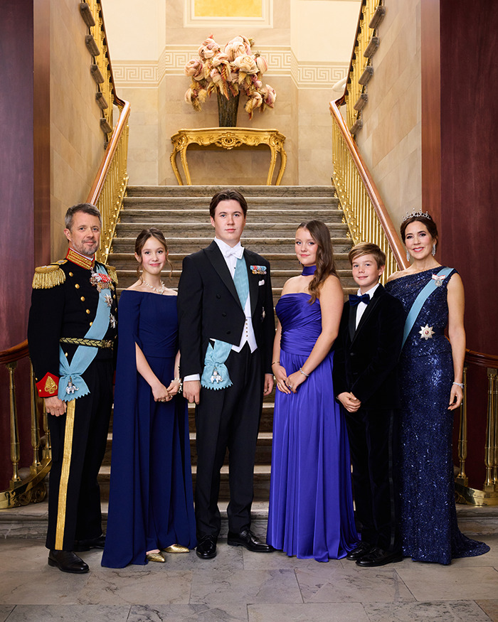Royal family in formal attire, posing on staircase, royal princess featured holding an iPhone in official portrait.