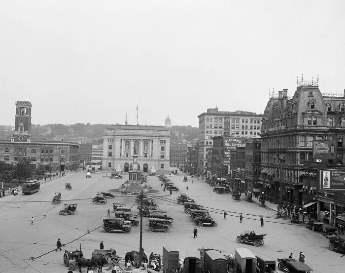 Historic black and white photo showing life in America 100 years ago with vintage cars and old city buildings.