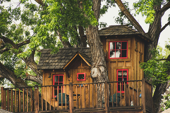 Wooden tree house surrounded by green leaves, evoking childhood memories of a sad daughter&rsquo;s past playtime spot.