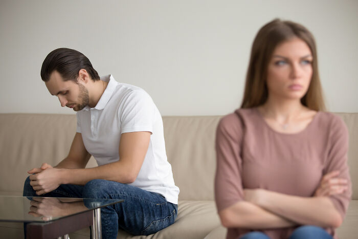 Woman and man sitting apart on a couch looking upset, illustrating ladies sharing red pill stories in relationships.