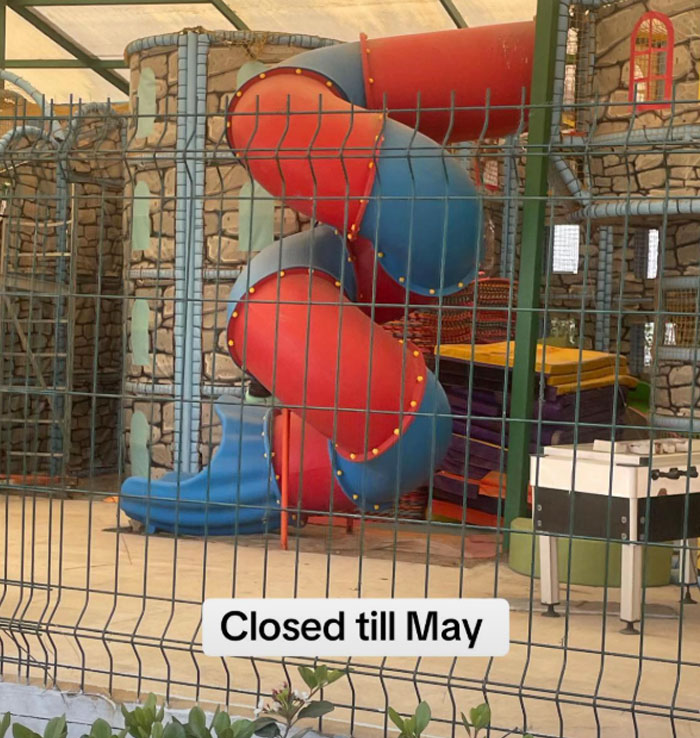 Closed water slide at Turkish resort, fenced off with a sign reading "Closed till May". Closed water slide at Turkish resort, fenced off with a sign reading "Closed till May".