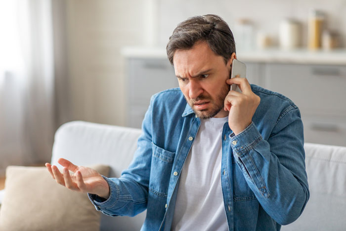 Man looking frustrated on a phone call, highlighting stereotypical school emergency call issues. Man looking frustrated on a phone call, highlighting stereotypical school emergency call issues.