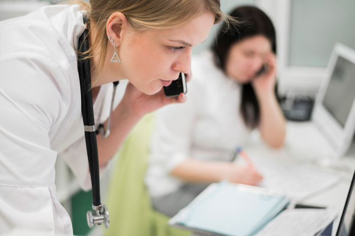 Healthcare worker on a phone call, addressing emergency situations in a hospital setting. Healthcare worker on a phone call, addressing emergency situations in a hospital setting.