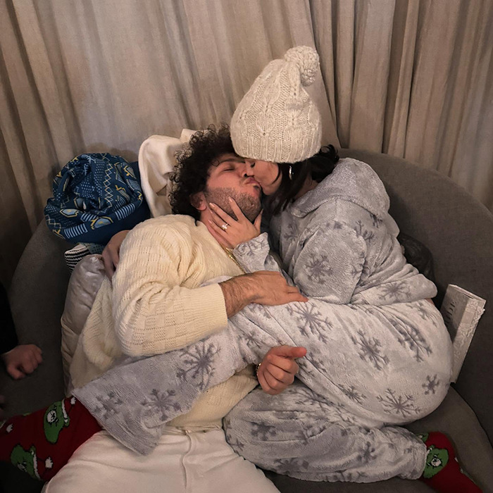 A couple in winter outfits kissing on a couch, highlighting intimate life elements.