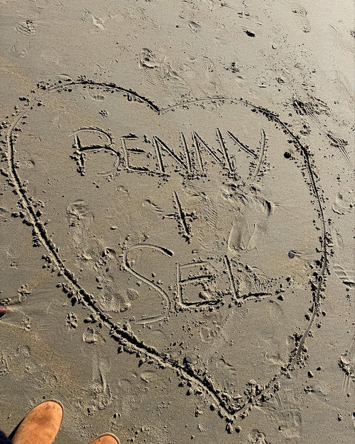 Heart drawn in sand with "Benny + Sel" inside, connected to intimate life theme.