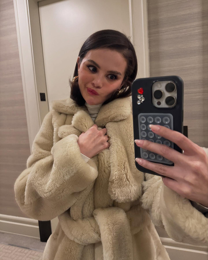 Woman in a fur coat takes a selfie, showcasing peek into intimate life.