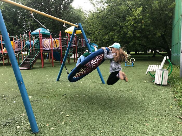 Children playing on a swing in a park, a nostalgic activity common 30 years ago, surrounded by playground structures.