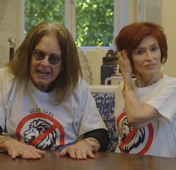 Two people sitting at a table, both wearing matching shirts, inside a well-lit room.