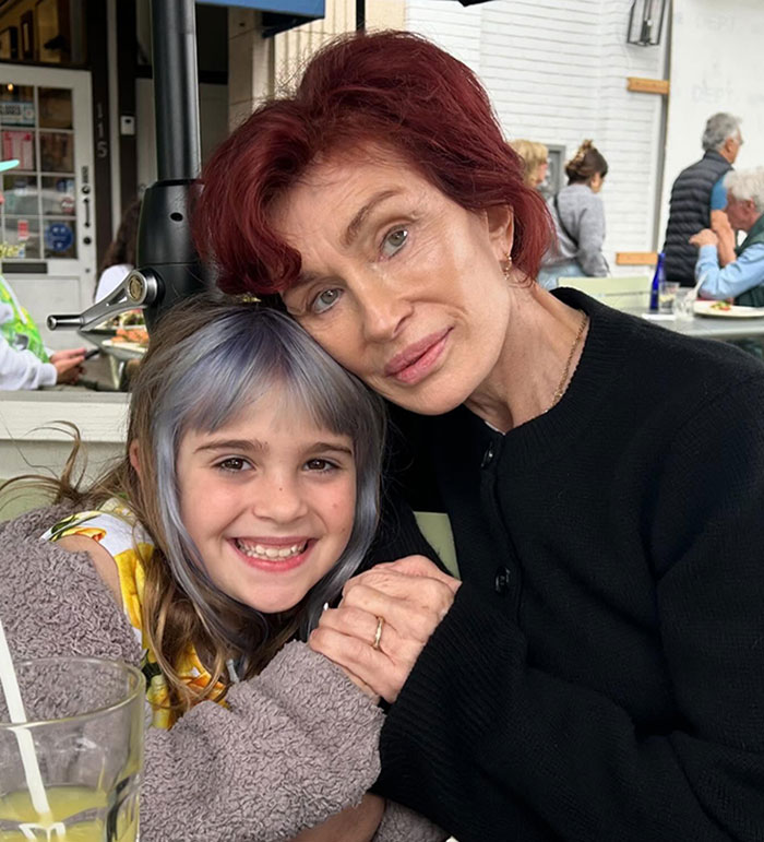 Woman with red hair and child with colorful hair smiling at a cafe, linked to Ozempic feet keyword discussion.