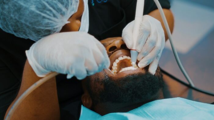 Patient receiving dental treatment from a doctor wearing gloves and a hair cover, highlighting unfair treatment from doctors.