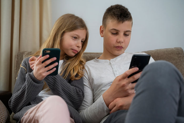 Siblings on a couch, each using a smartphone, representing how siblings interact with technology at home. Siblings on a couch, each using a smartphone, representing how siblings interact with technology at home.