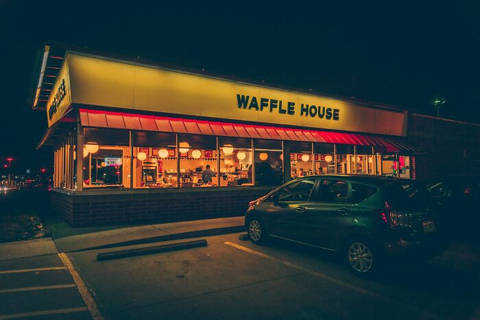 Waffle House at night with bright interior lighting, showcasing a deserted parking lot.