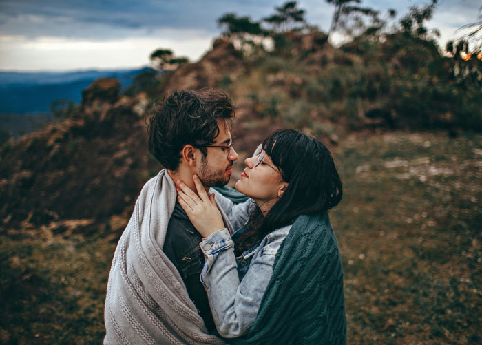 A couple wrapped in blankets embraces on a scenic mountain top. A couple wrapped in blankets embraces on a scenic mountain top.