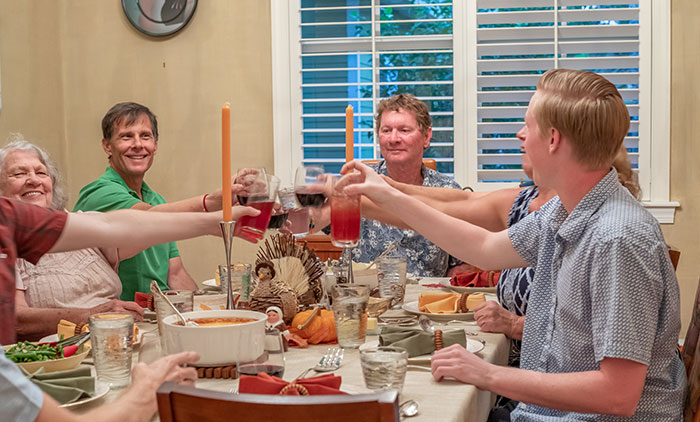 Family gathered around the dining table, raising glasses during a traditional celebration, highlighting family and tradition themes. Family gathered around the dining table, raising glasses during a traditional celebration, highlighting family and tradition themes.