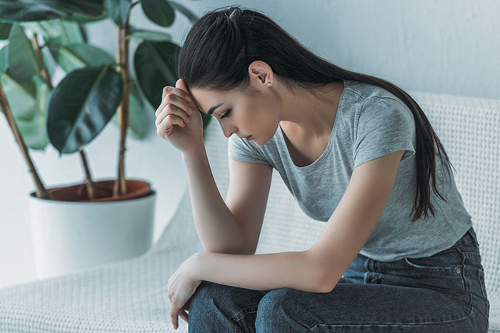 Young woman looking upset and thoughtful indoors, reflecting on quickly shutting down sister after trying to change tradition Young woman looking upset and thoughtful indoors, reflecting on quickly shutting down sister after trying to change tradition