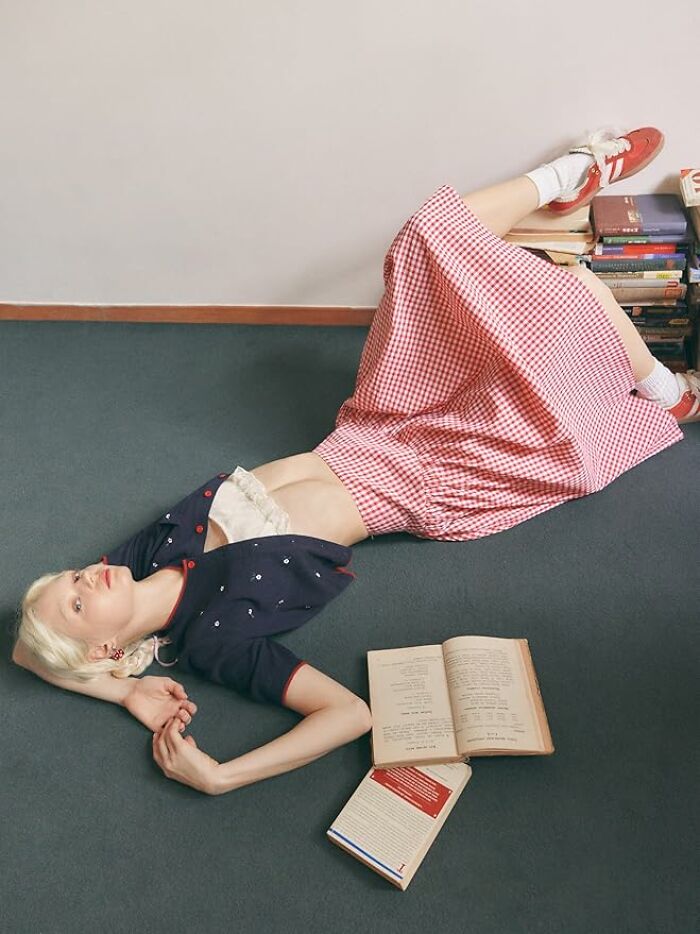 Person in a vintage outfit relaxing on floor with books—festival survival kit essentials.