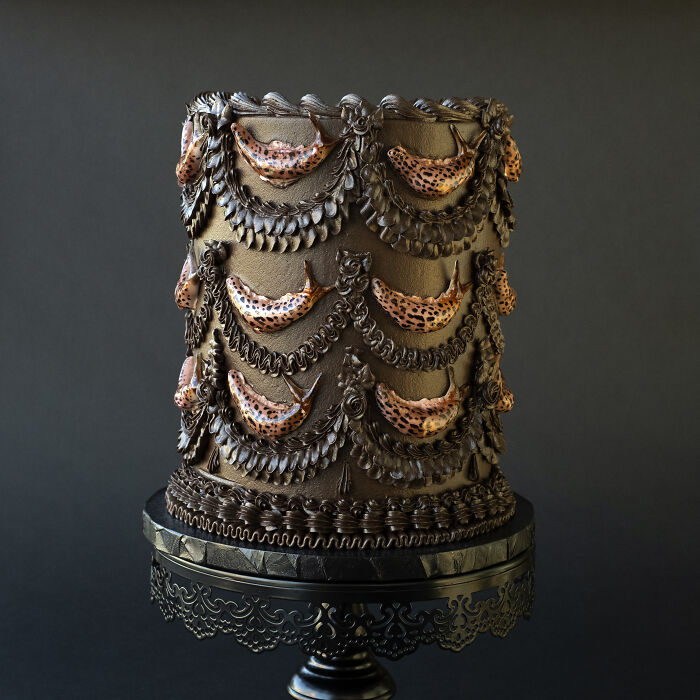 Vegan cake decorated with realistic slugs, set against a dark background.