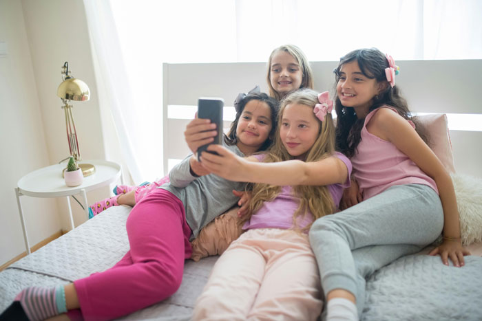 Girls taking a selfie during a softball team sleepover, enjoying snacks and pizza. Girls taking a selfie during a softball team sleepover, enjoying snacks and pizza.