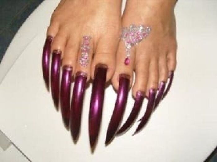 Long purple toenails with gemstone decorations, giving off wild psychopath vibes.