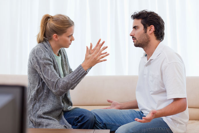 Man and woman having a tense discussion indoors, reflecting conflict about dad catching teen son creeping around neighbor&rsquo;s yard.