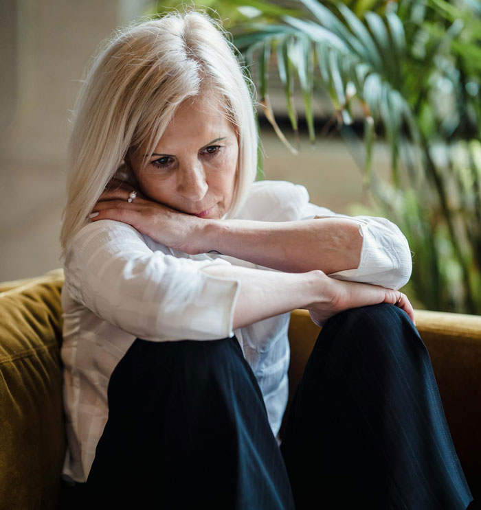 A contemplative mother sitting with crossed arms, concerned about her kids and their controlling stepdad. A contemplative mother sitting with crossed arms, concerned about her kids and their controlling stepdad.