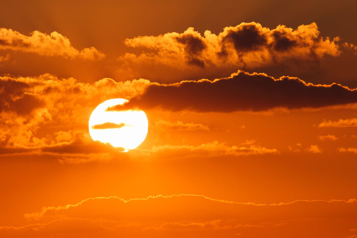 Sunset behind clouds, illustrating serene adult moments with a warm orange glow.