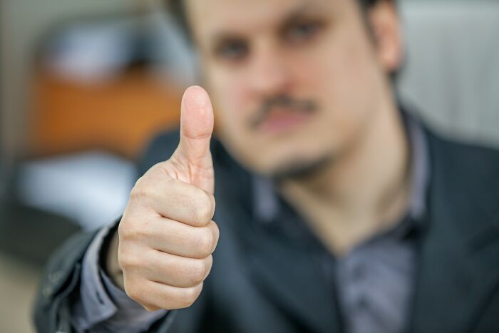 A man in a suit gives a thumbs up, symbolizing positive explain-adult-moments in a professional setting.