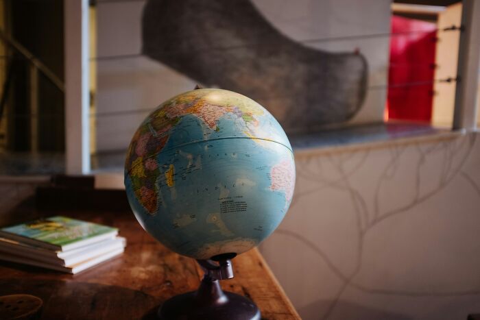 A globe on a wooden table, with books nearby, illustrating educational adult moments.