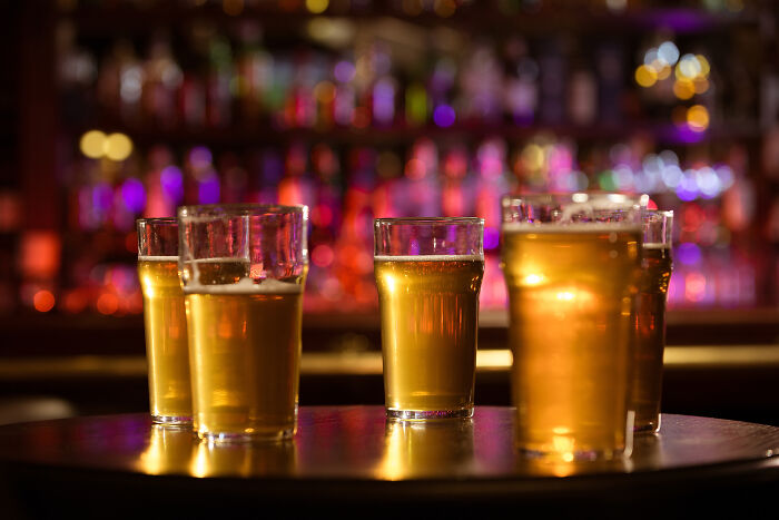 Glasses of beer on a bar table with blurred colorful lights, representing adult moments in a social setting.