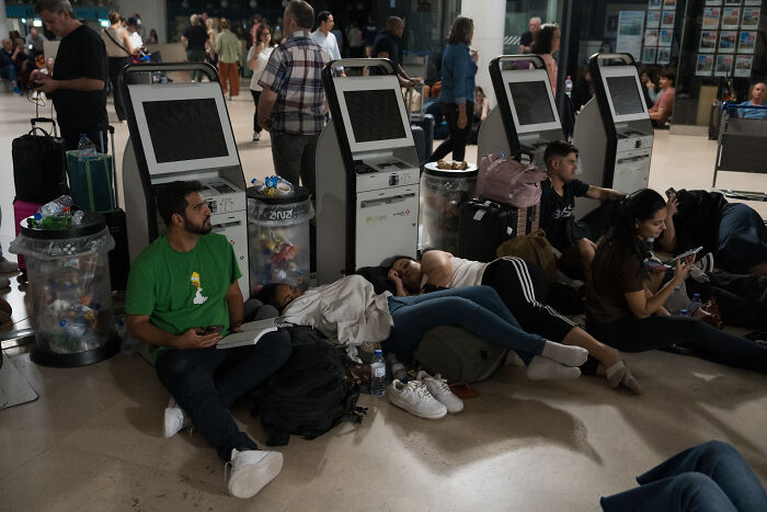 People waiting and resting near unused kiosks during a major blackout paralyzing activities for millions in Europe