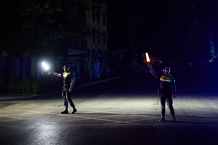 Two police officers directing traffic at night during a major blackout affecting millions in Europe.