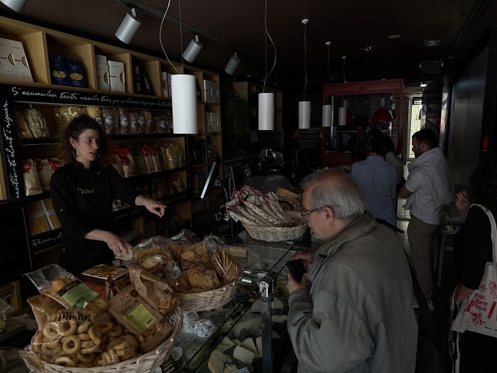 Dark grocery store interior during major blackout, with customers and staff navigating nearly paralyzed activities.