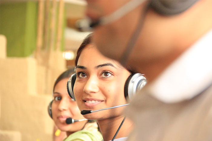 Call center employees at work with headsets, focusing on spam caller interactions.