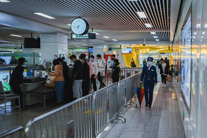 Passengers going through airport security, illustrating 'SSSS' code-related flight delays. Passengers going through airport security, illustrating 'SSSS' code-related flight delays.
