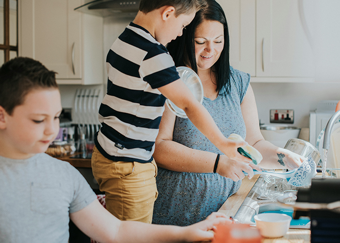 Mother and children in kitchen, doing dishes together, focusing on chores and family teamwork.