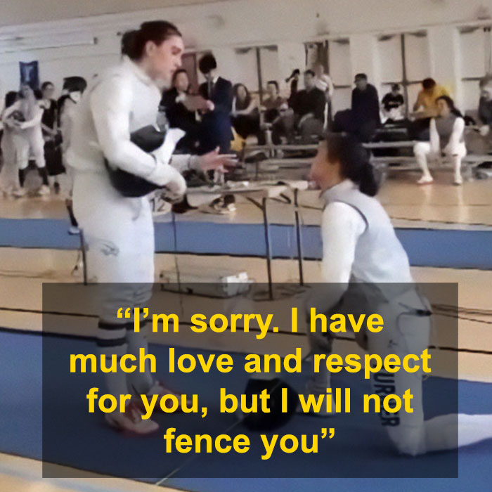 Trans athlete kneeling in fencing gear amidst controversy, surrounded by team members in a gymnasium.