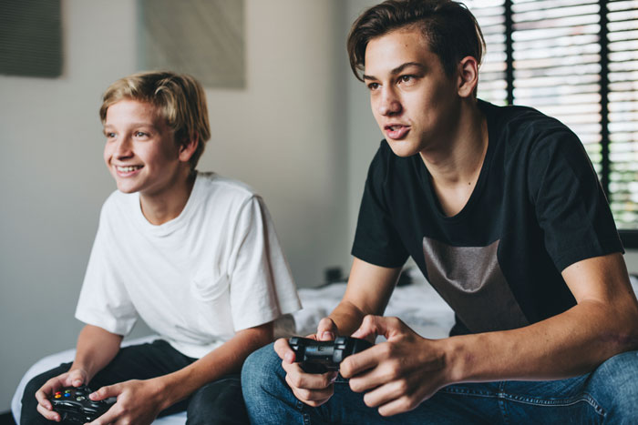Teenagers playing video games intently indoors, concentrating on their game controllers.