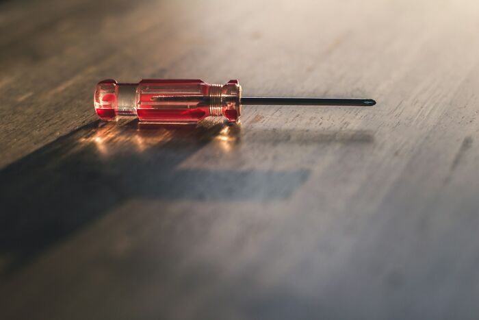 A red-handled screwdriver on a wooden surface, relating to disturbing discoveries by doctors in patients.