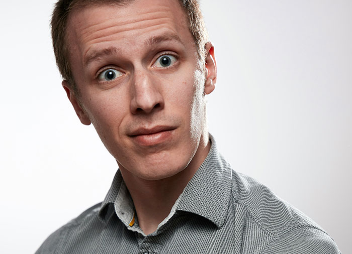 A surprised man in a gray shirt expressing shock in response to a casual admission.