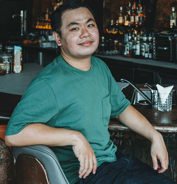 Man in green shirt sitting casually at a bar, embodying a relaxed admission of something unusual.