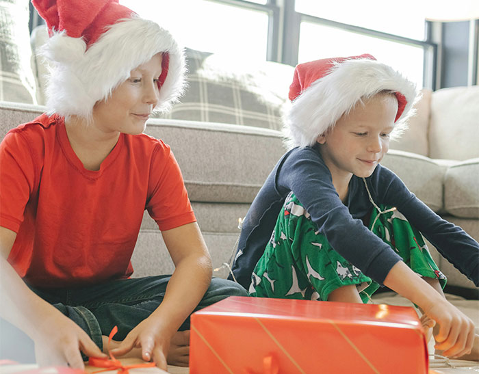 Children in Santa hats wrapping gifts, capturing the essence of crazy coincidences during the holiday season.